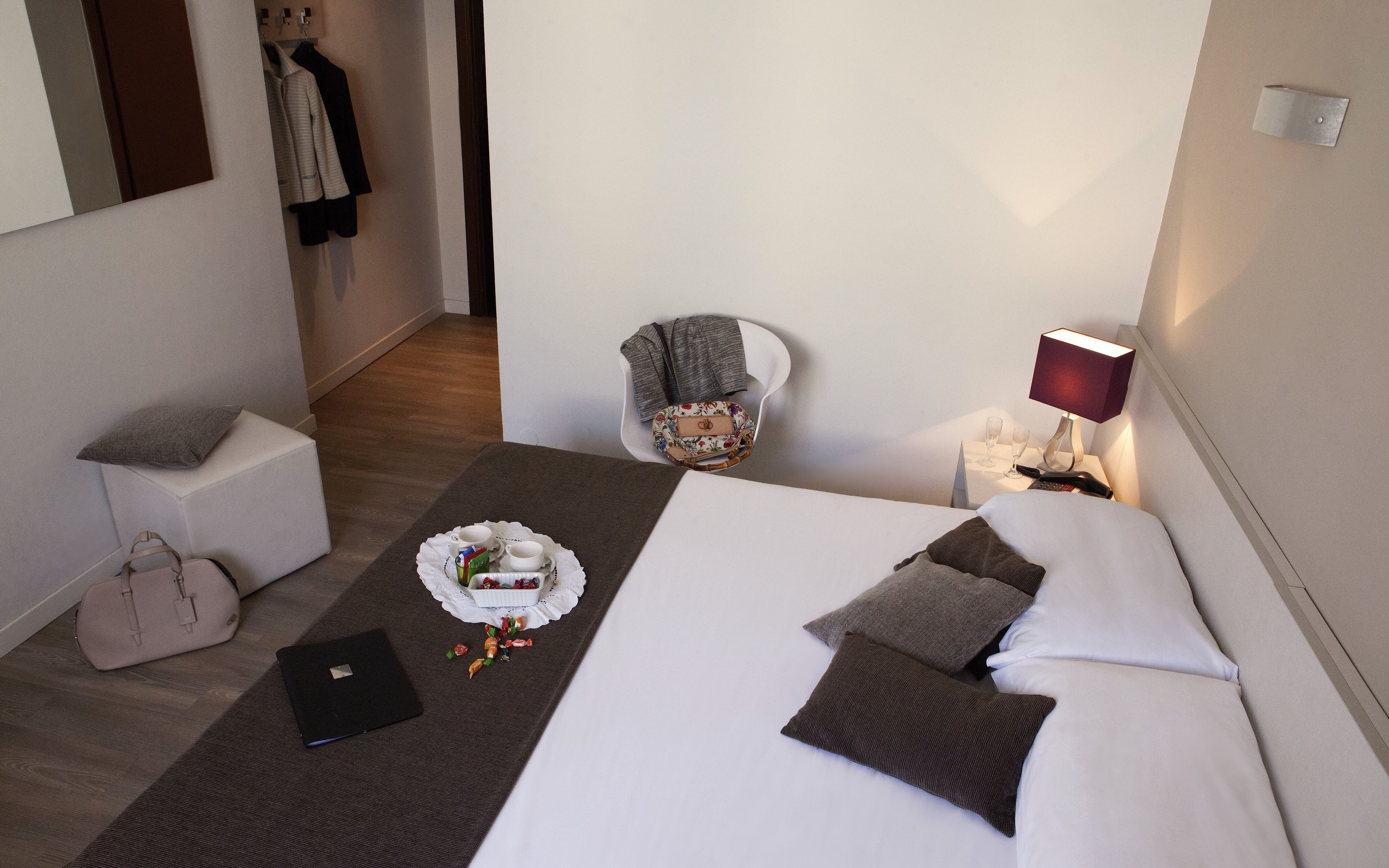 Ett hotellrum med en säng, en stol, ett skrivbord och en lampa.