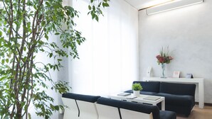 Uma sala de estar moderna com um sofá branco, um sofá preto, uma mesa de centro branca e uma planta em vaso.