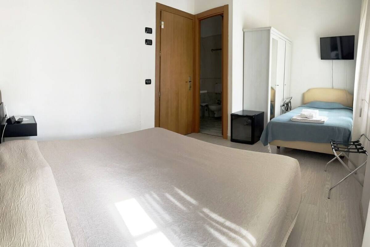 Ein Schlafzimmer mit Bett, Fernseher, Kleiderschrank und angrenzendem Badezimmer.