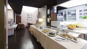 Uma mesa de buffet com diversos alimentos e uma cesta de frutas.