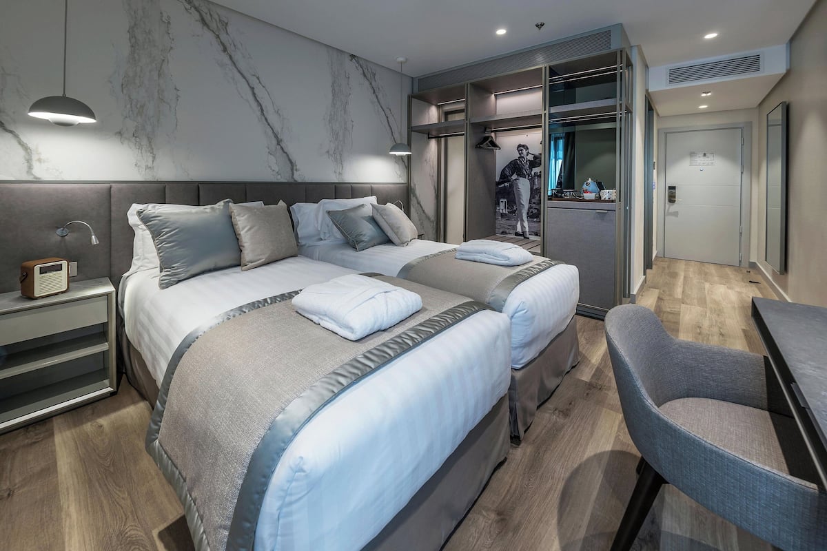 A modern hotel room with a large bed, bedside tables, a desk, and a chair.