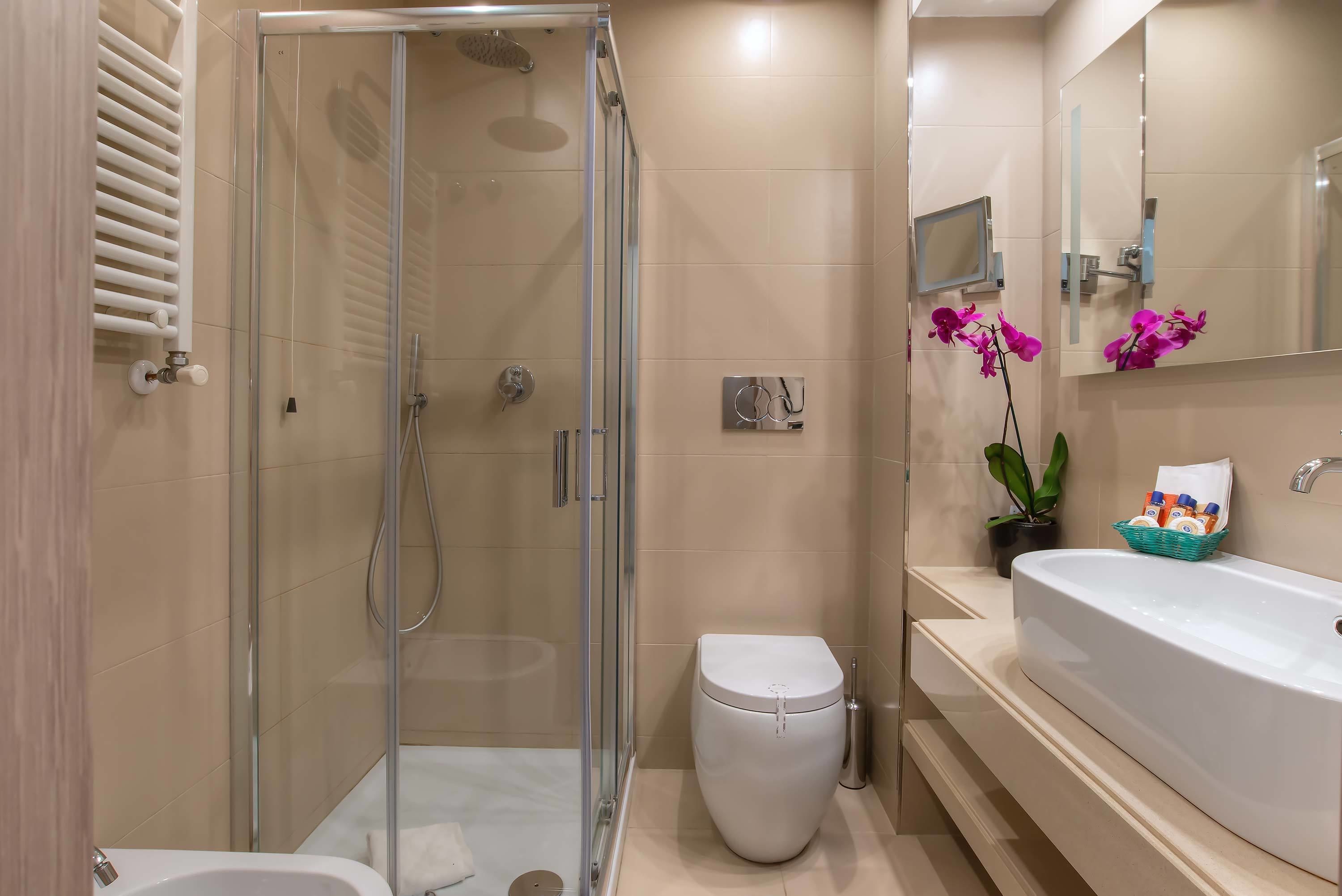 A modern bathroom with a glass-enclosed shower, a white toilet, a large sink, and a mirror.