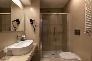 A modern bathroom with a large white sink, a glass-enclosed shower, and a toilet.