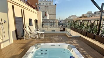 A rooftop terrace with a hot tub, lounge chairs, and a pergola.