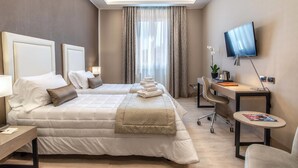 Une chambre d’hôtel avec un grand lit, un bureau, une chaise, une télévision et une fenêtre avec des rideaux.