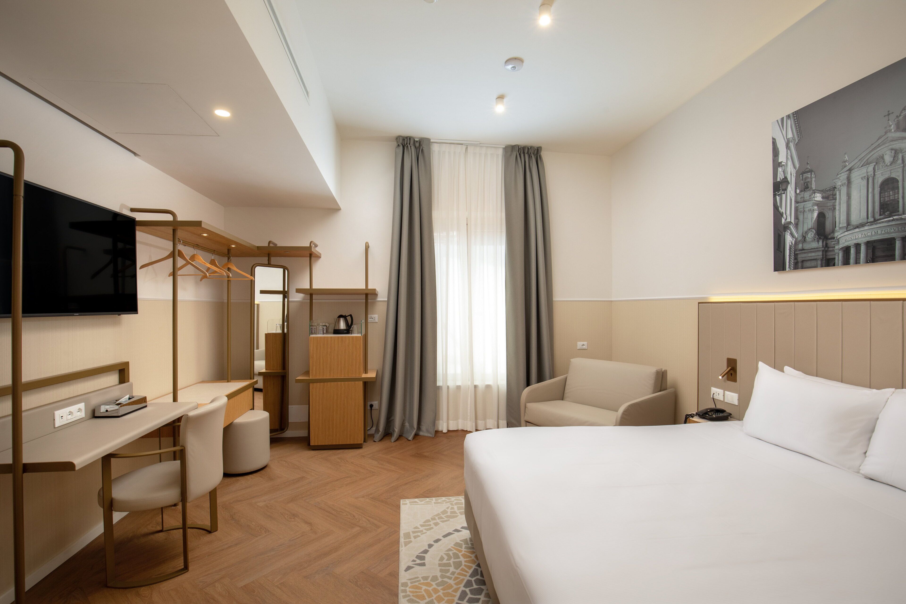 Une chambre d’hôtel moderne équipée d’un lit, d’un bureau, d’une chaise, d’une télévision et d’une armoire.