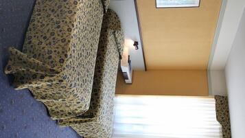Una camera d'hotel con un letto, una sedia, una scrivania con un computer e una finestra con persiane.