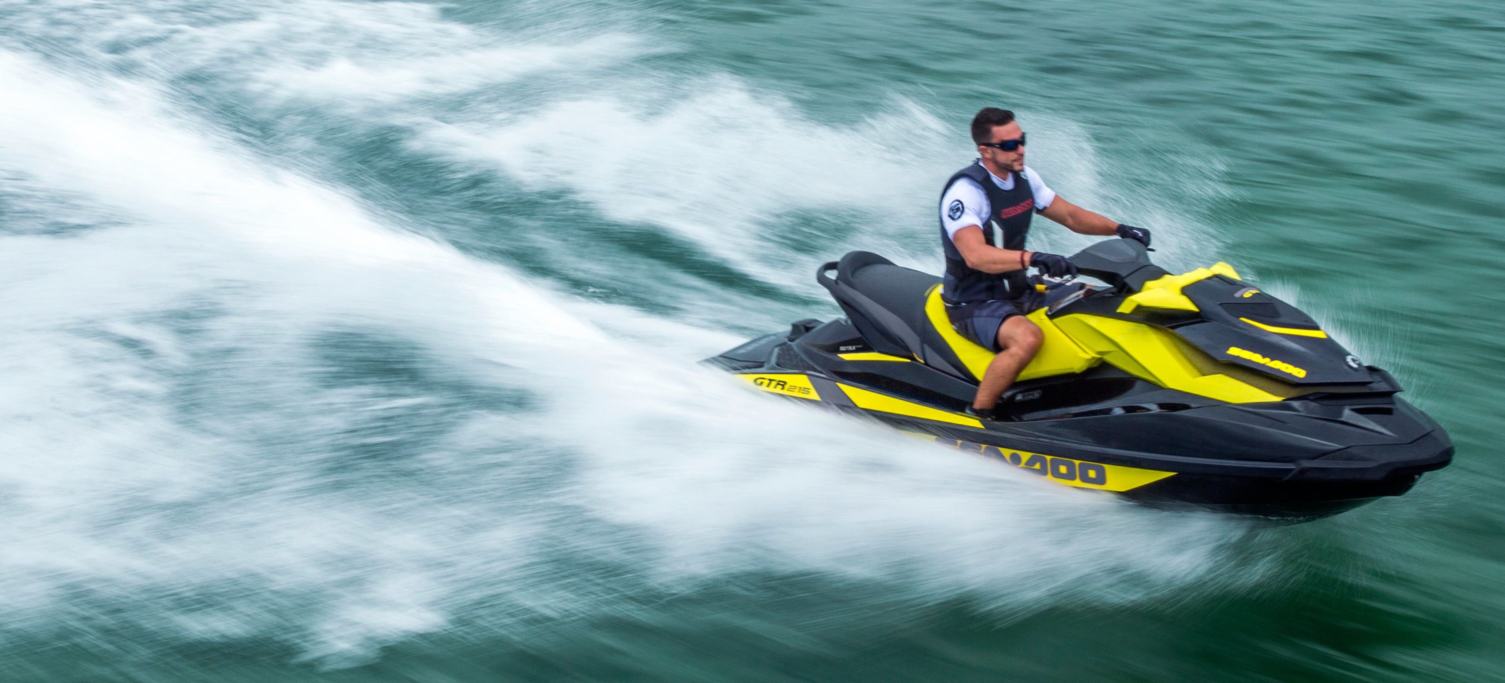 Una persona conduce un jet ski amarillo y negro sobre el agua.