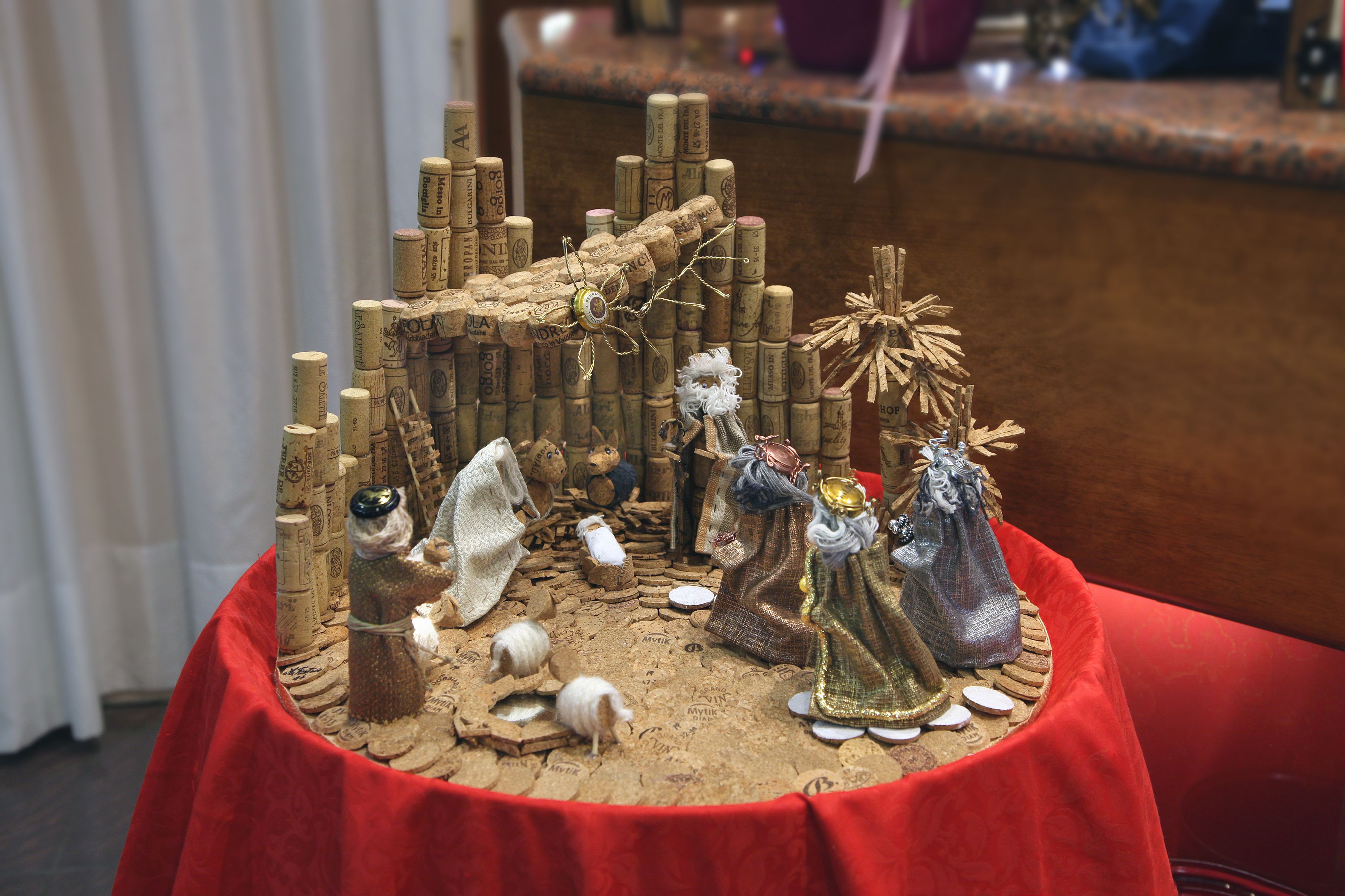 Presepe con statuine e uno sfondo raffigurante una stalla realizzato con tappi di vino.