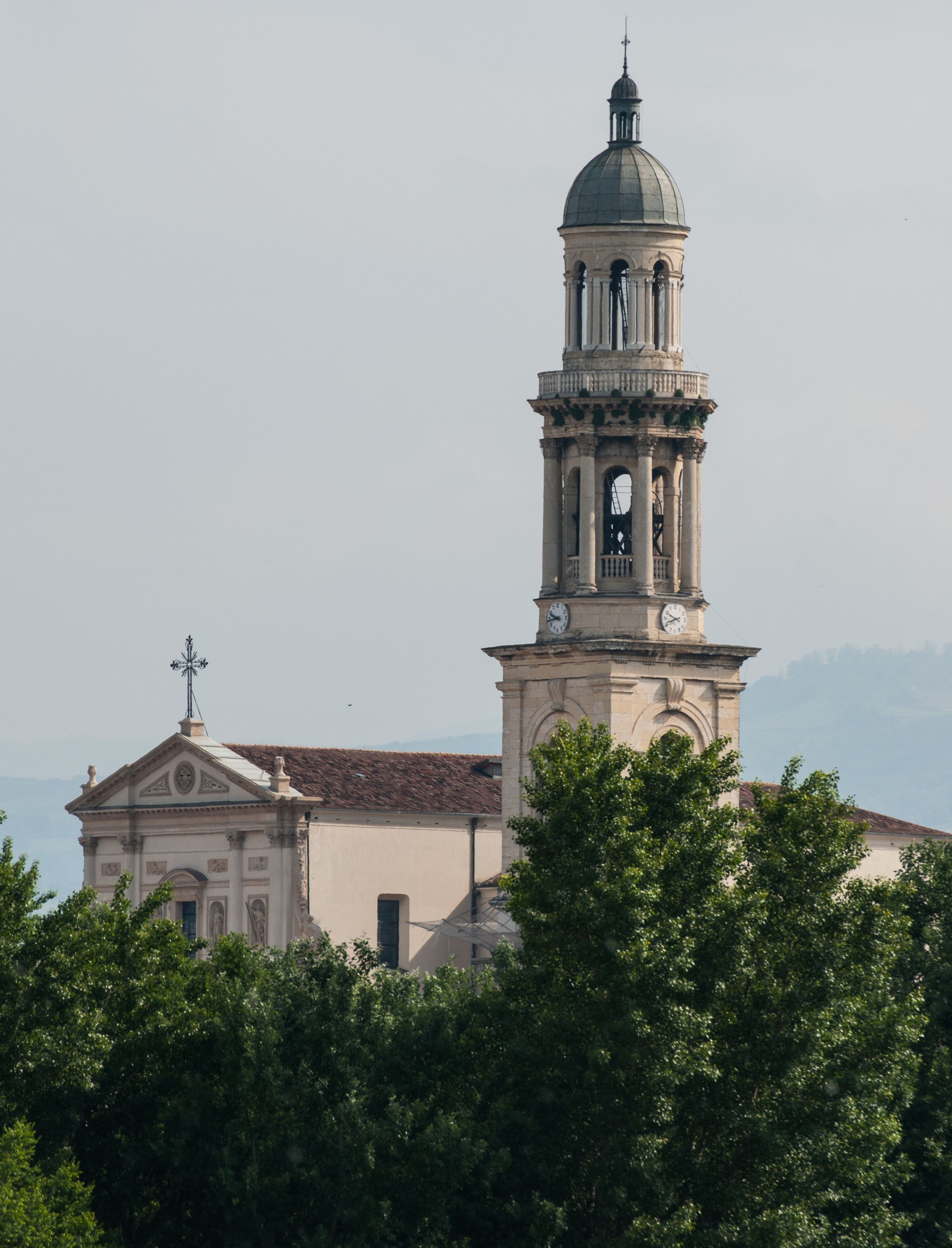 A church with a bell tower and a dome, surrounded by trees.