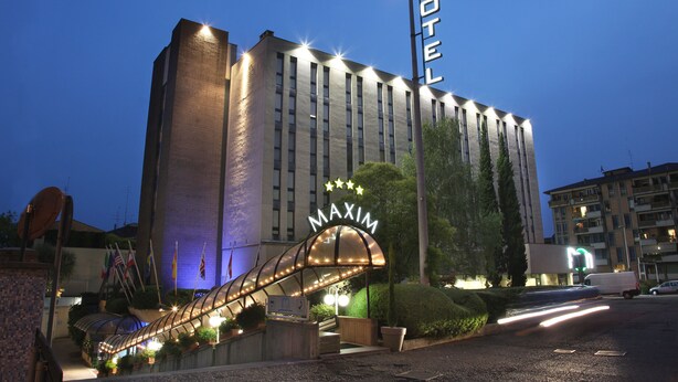 Un hotel con un letrero visible, un acceso cubierto y una fachada bien iluminada.