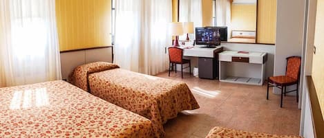 Una habitación de hotel con dos camas, un escritorio, una silla y un televisor.
