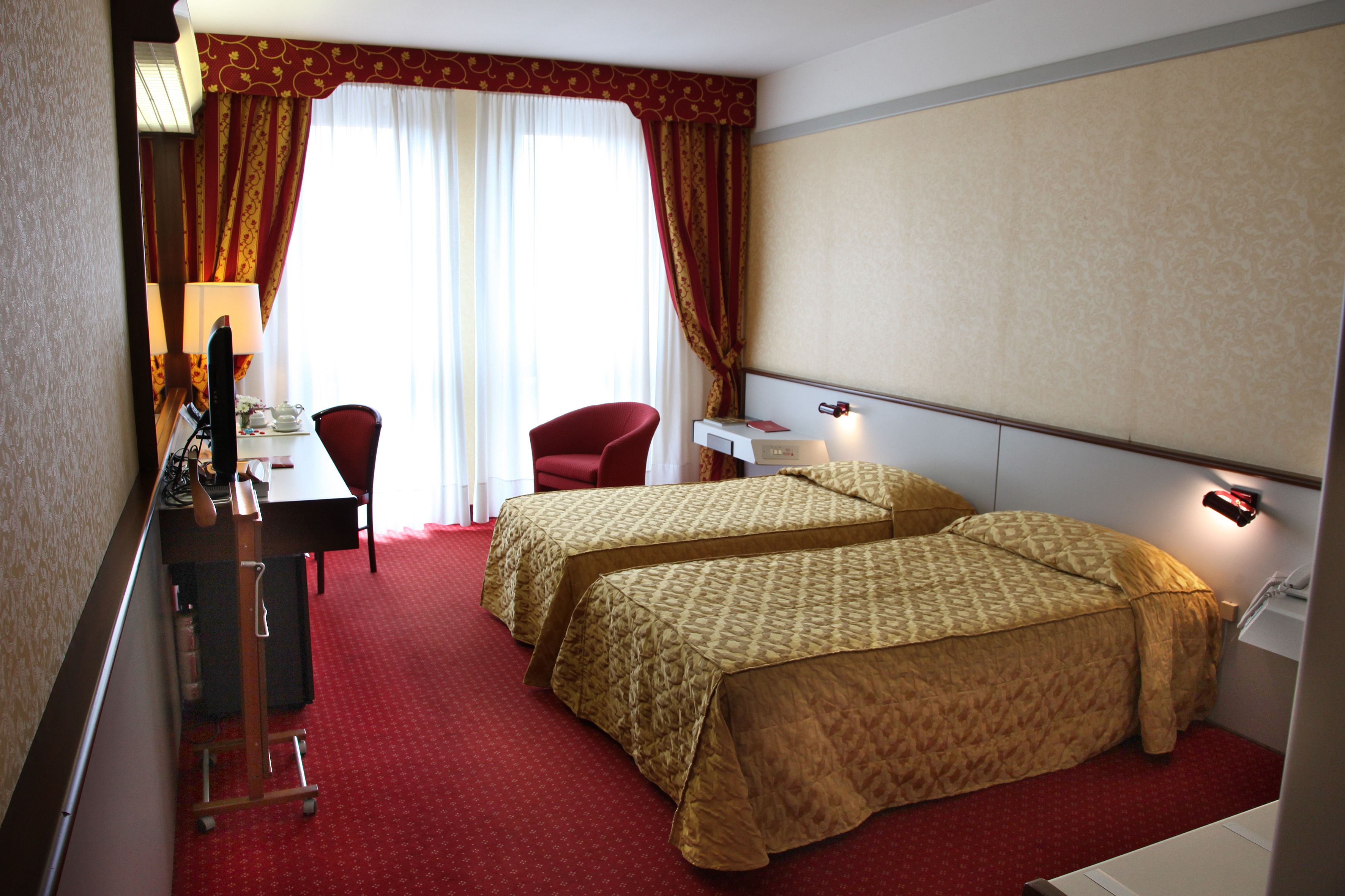 Una habitación de hotel con dos camas, un escritorio, una silla y una lámpara.