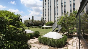 Un edificio moderno con un patio que cuenta con senderos de piedra, setos bien cuidados y una escalera que conduce a un nivel superior.