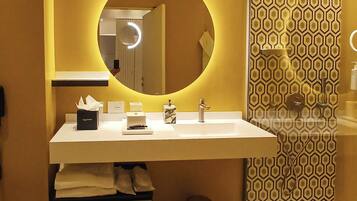 A modern bathroom with a round mirror, a white sink, and a patterned wall.