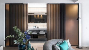 A modern interior with a sofa, a vase with flowers, and a wooden partition. - Hotel Plaza e de Russie (Viareggio)