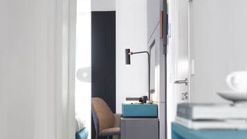Una camera d'albergo moderna con una scrivania, una sedia e un letto sullo sfondo.
