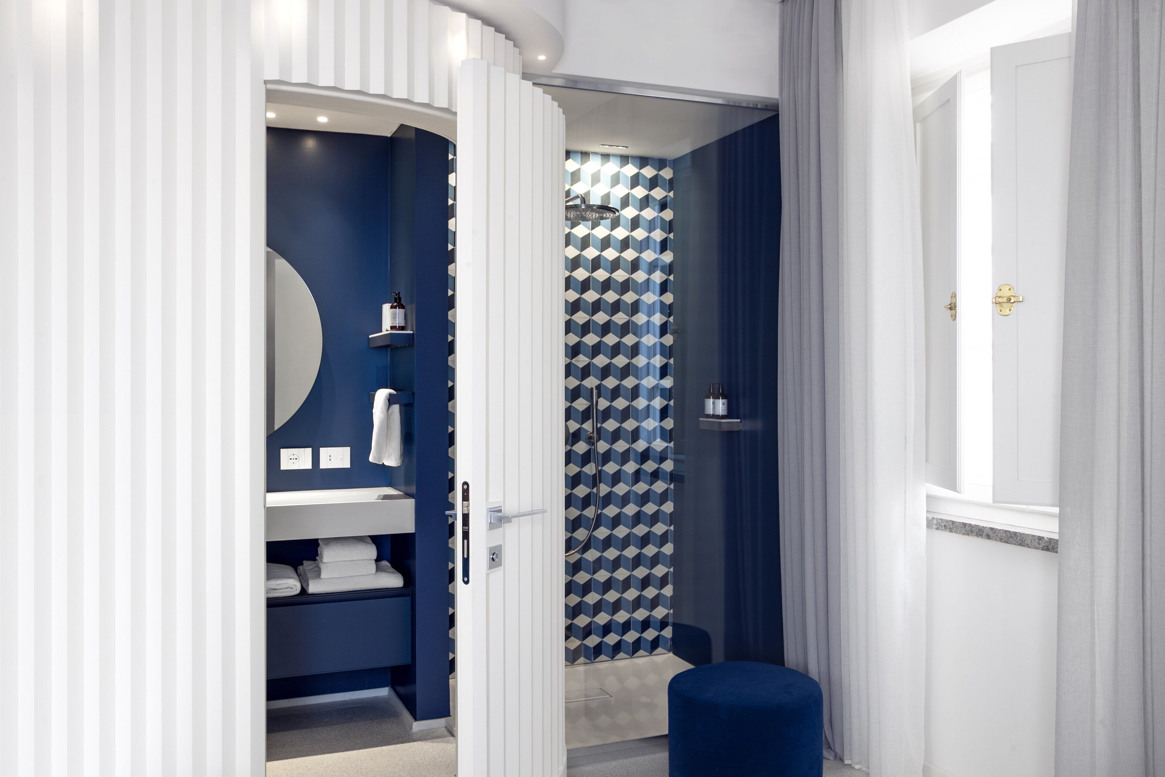 Un bagno moderno con colori blu e bianchi, dotato di doccia, lavandino e specchio.