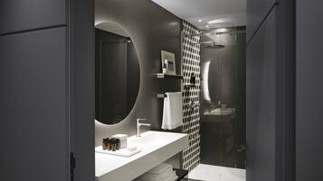 A modern bathroom with a large mirror, white sink, and a glass shower enclosure.