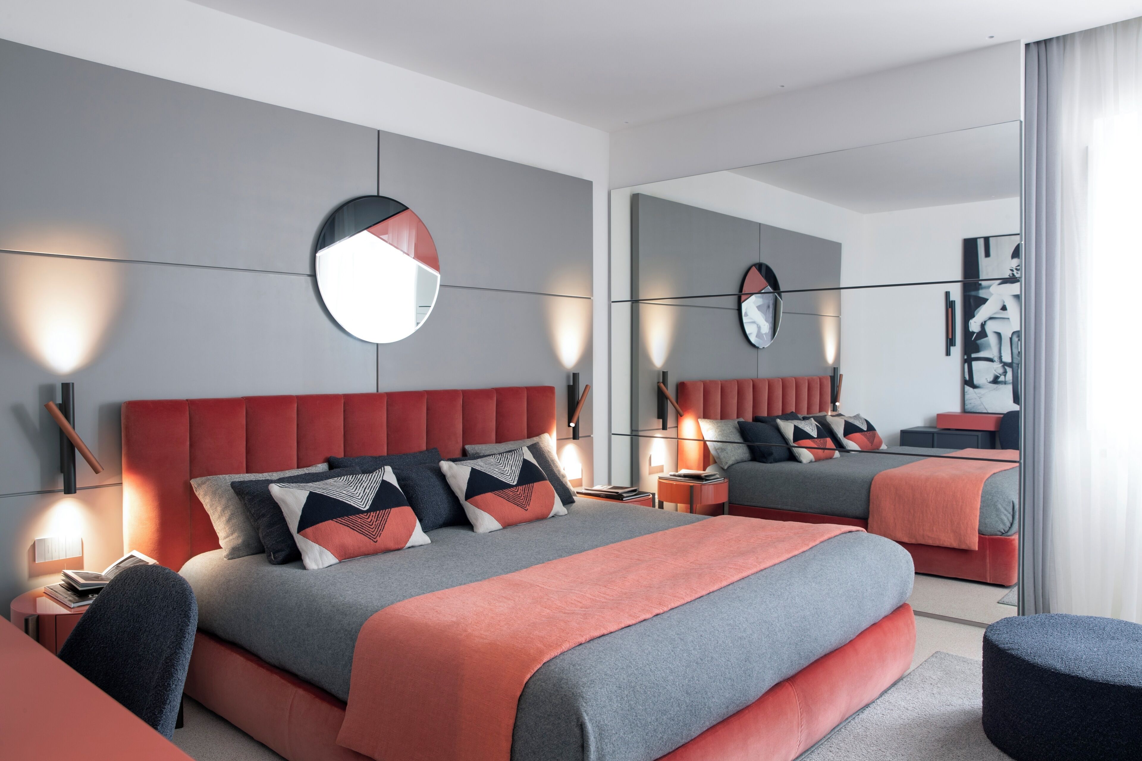 A modern bedroom with a large bed, bedside tables, a mirror, and a nightstand.