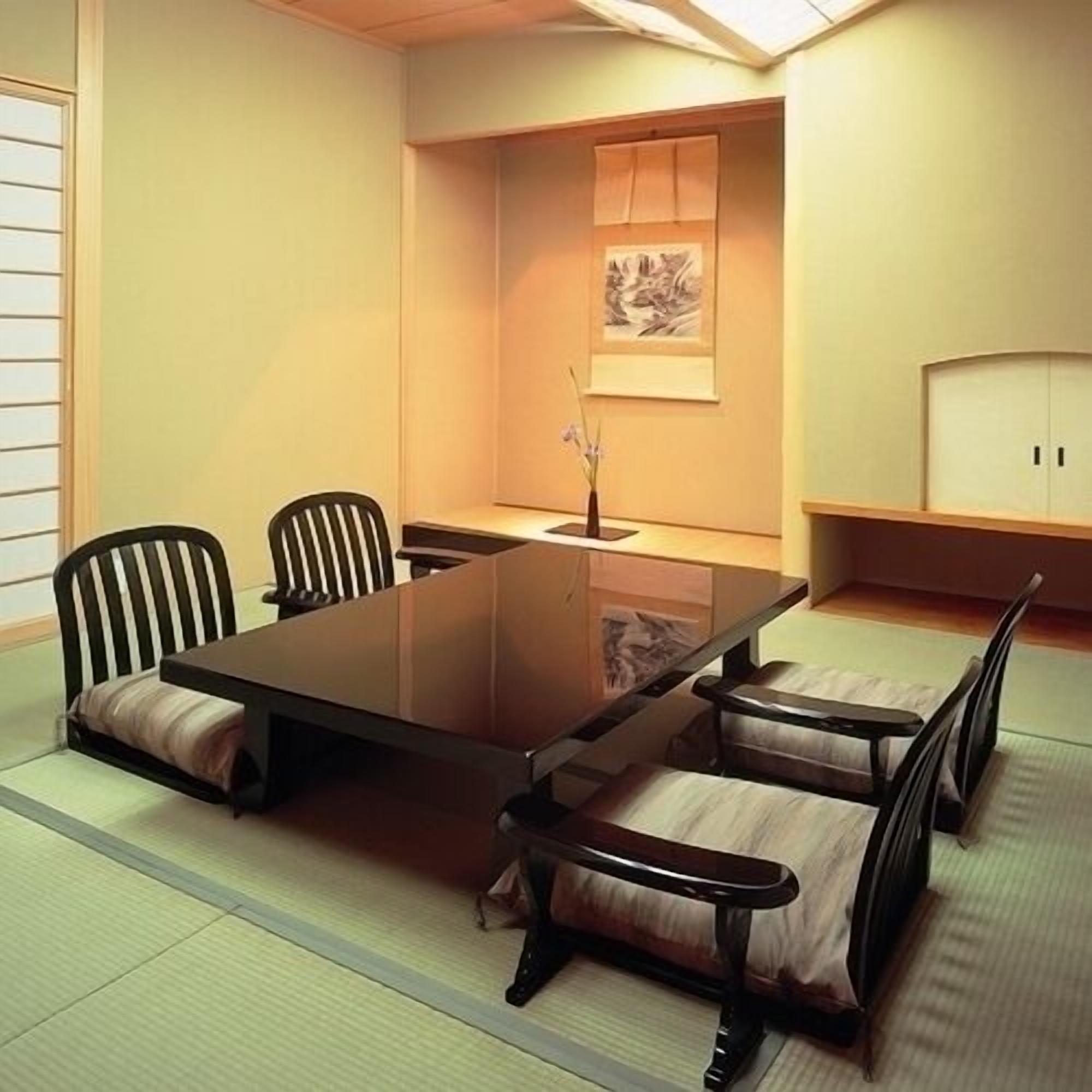 A traditional Japanese-style room with tatami flooring, a low table, and wooden chairs.