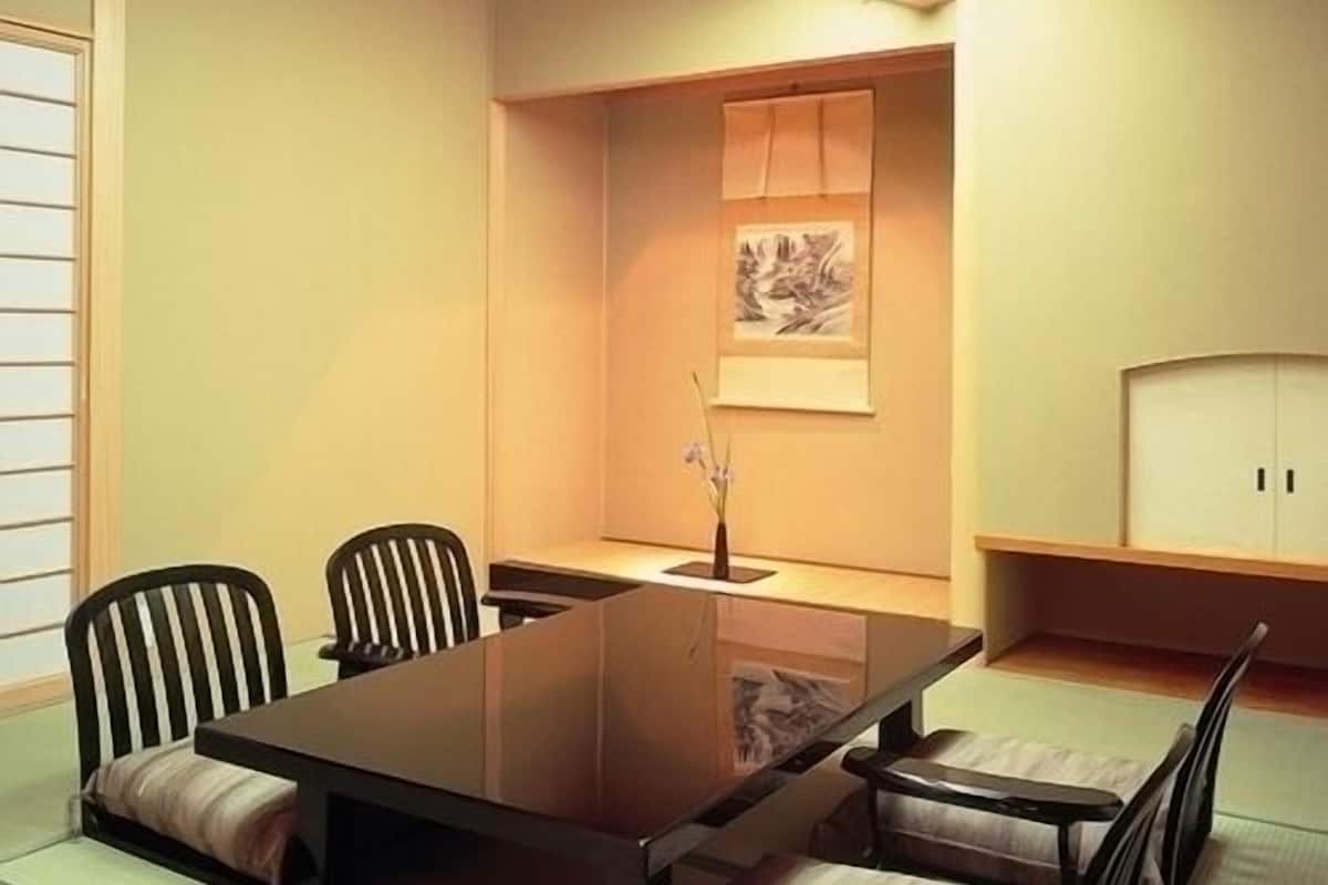 A traditional Japanese-style room with tatami flooring, a low table, and wooden chairs.