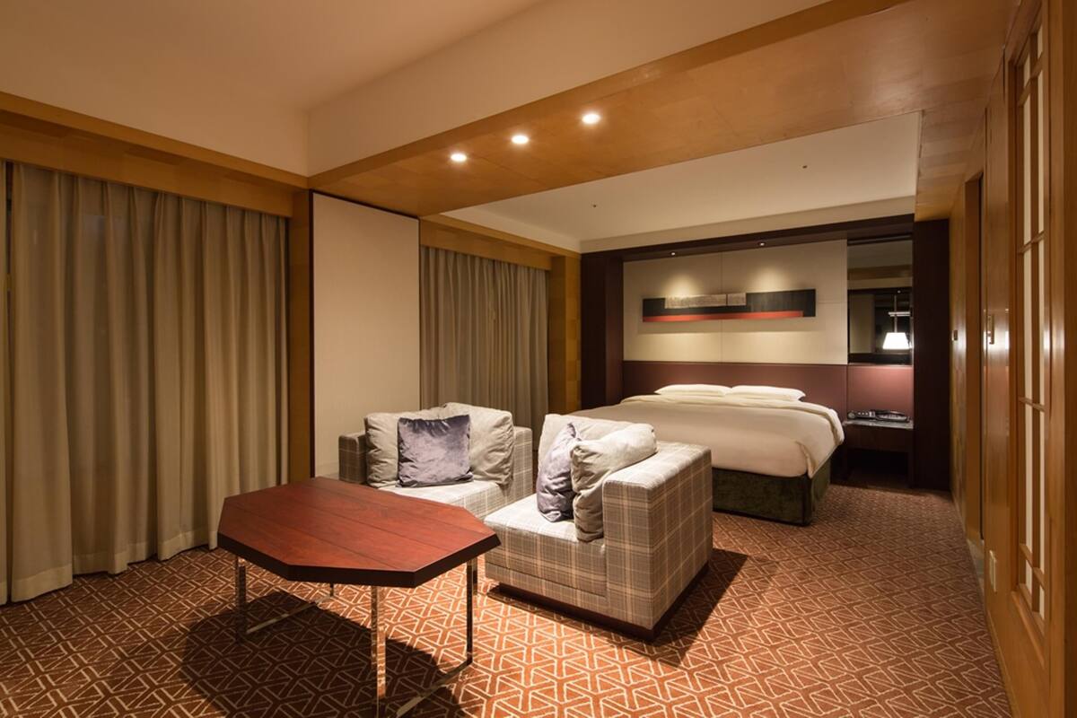Ein Hotelzimmer mit einem Bett, zwei Sofas, einem Holztisch und einem gemusterten Teppich.