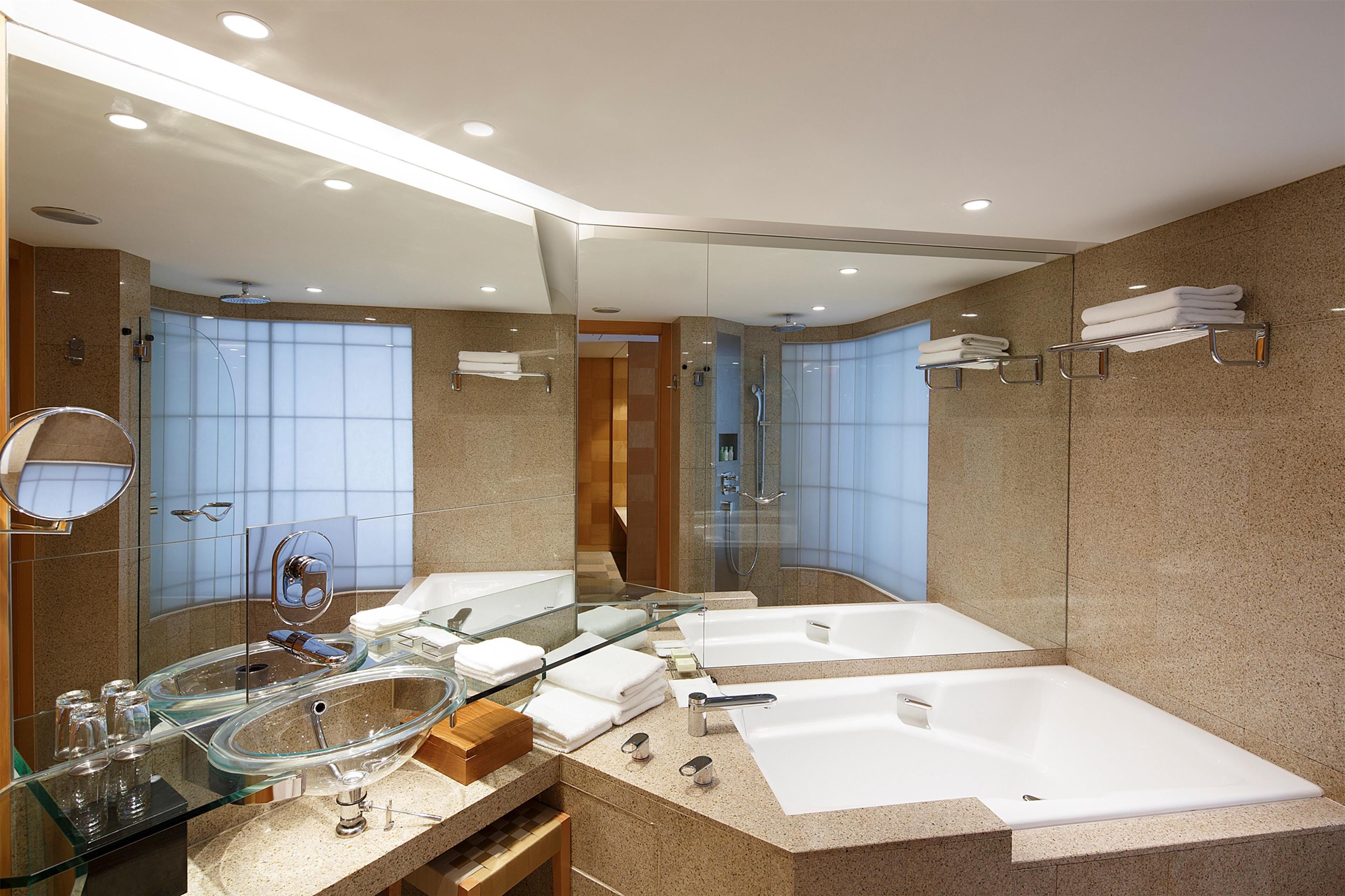 A modern bathroom with a glass-enclosed shower, a double sink, and a large bathtub.