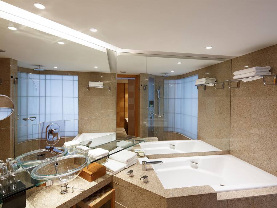 A modern bathroom with a glass-enclosed shower, a double sink, and a large bathtub.