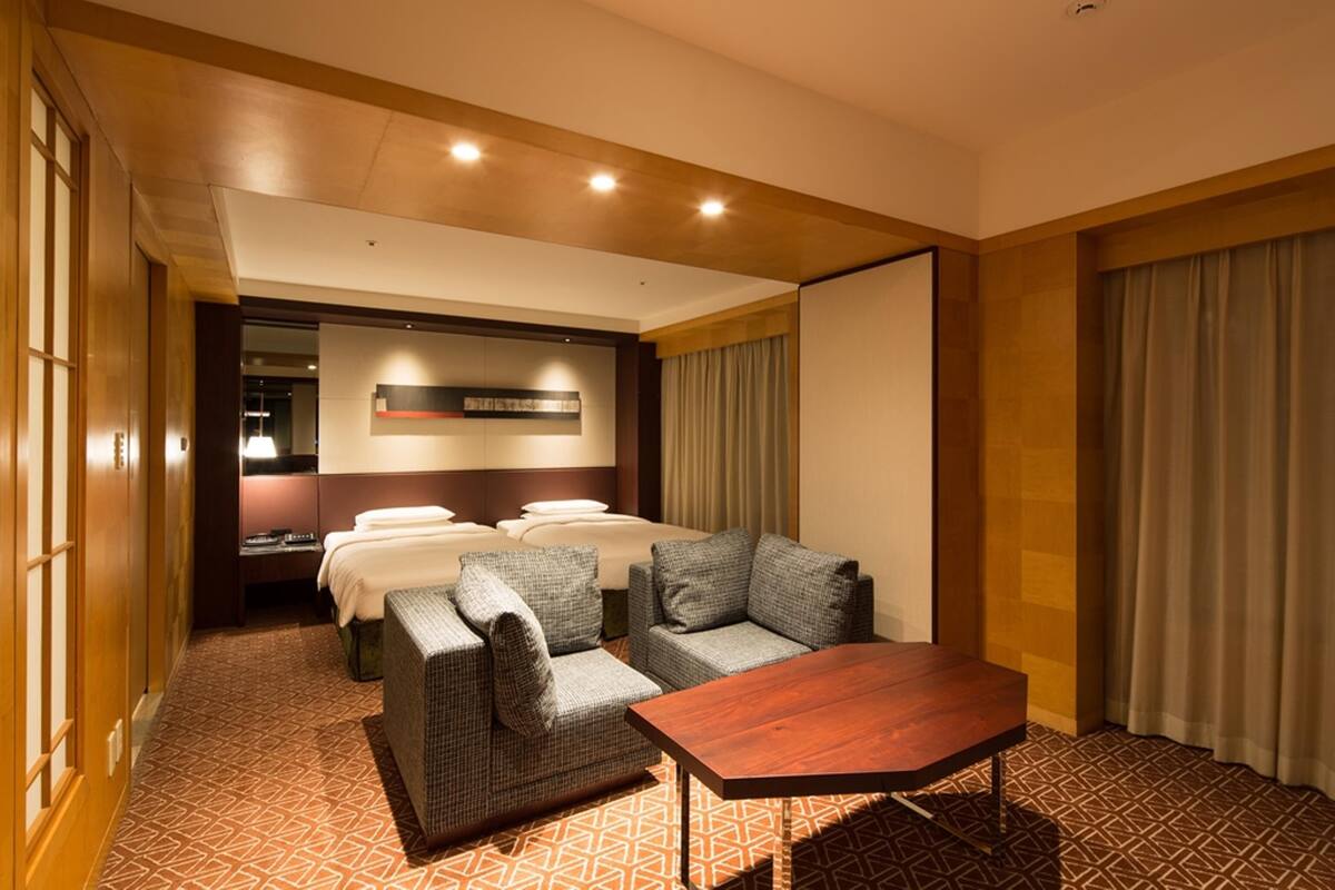 Ein Hotelzimmer mit einem Bett, zwei Sofas, einem Holztisch und einem gemusterten Teppich.