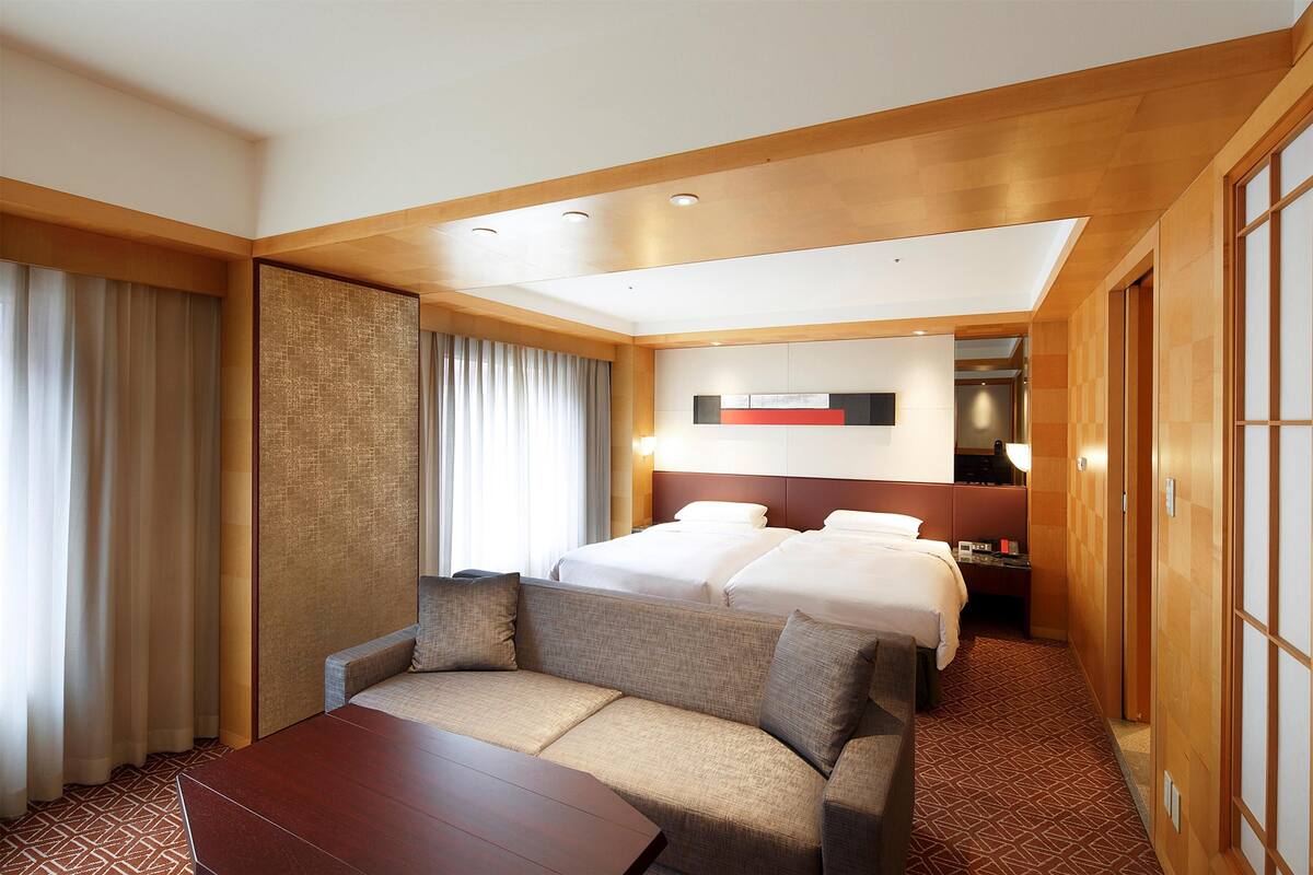 Ein Hotelzimmer mit einem großen Bett, einer Couch, einem Schreibtisch und einem Spiegel.