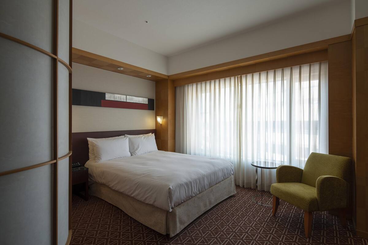 Ein Hotelzimmer mit einem großen Bett, einem kleinen Tisch und einem Stuhl.
