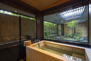 A traditional Japanese-style bath with a wooden interior and a view of a bamboo garden. - Grand Hyatt Fukuoka (Fukuoka)