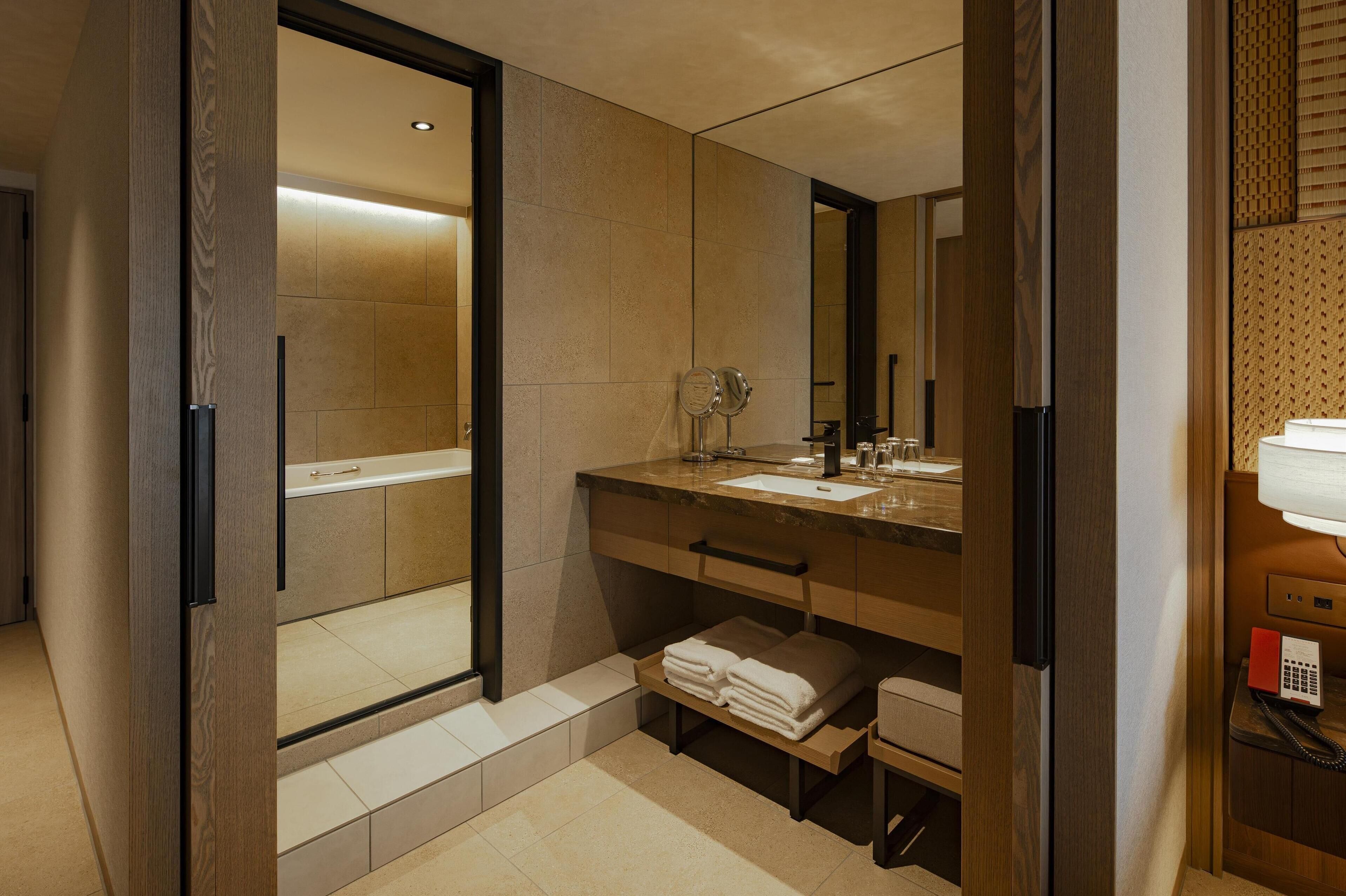 A modern bathroom with a walk-in shower, a vanity with a sink, and a mirror.
