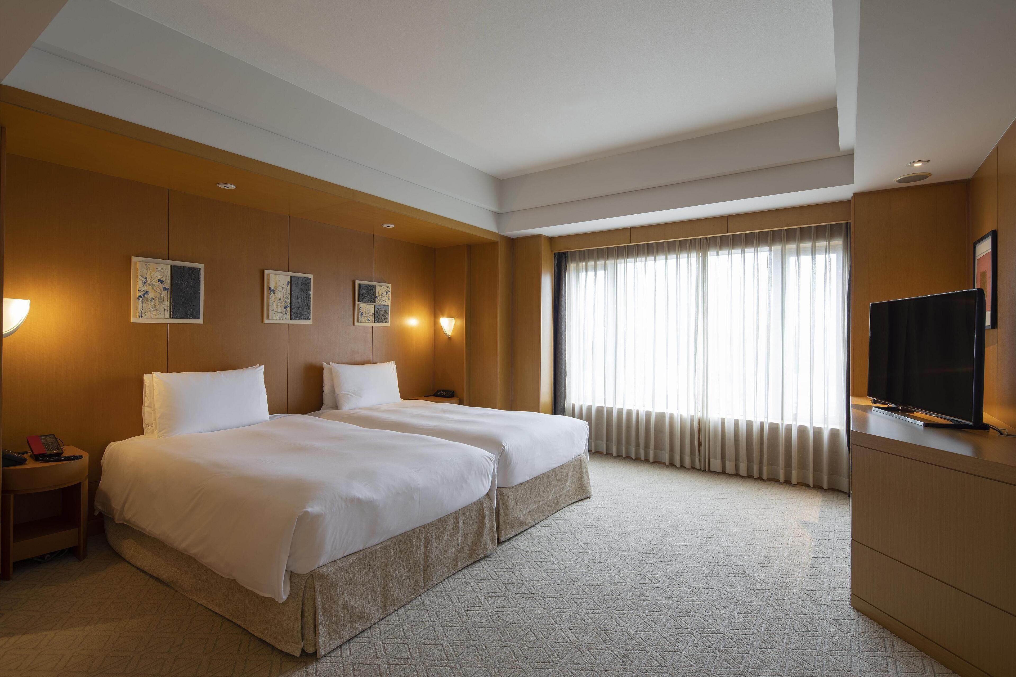Une chambre d’hôtel avec deux lits, une télévision et des œuvres d’art accrochées au mur.
