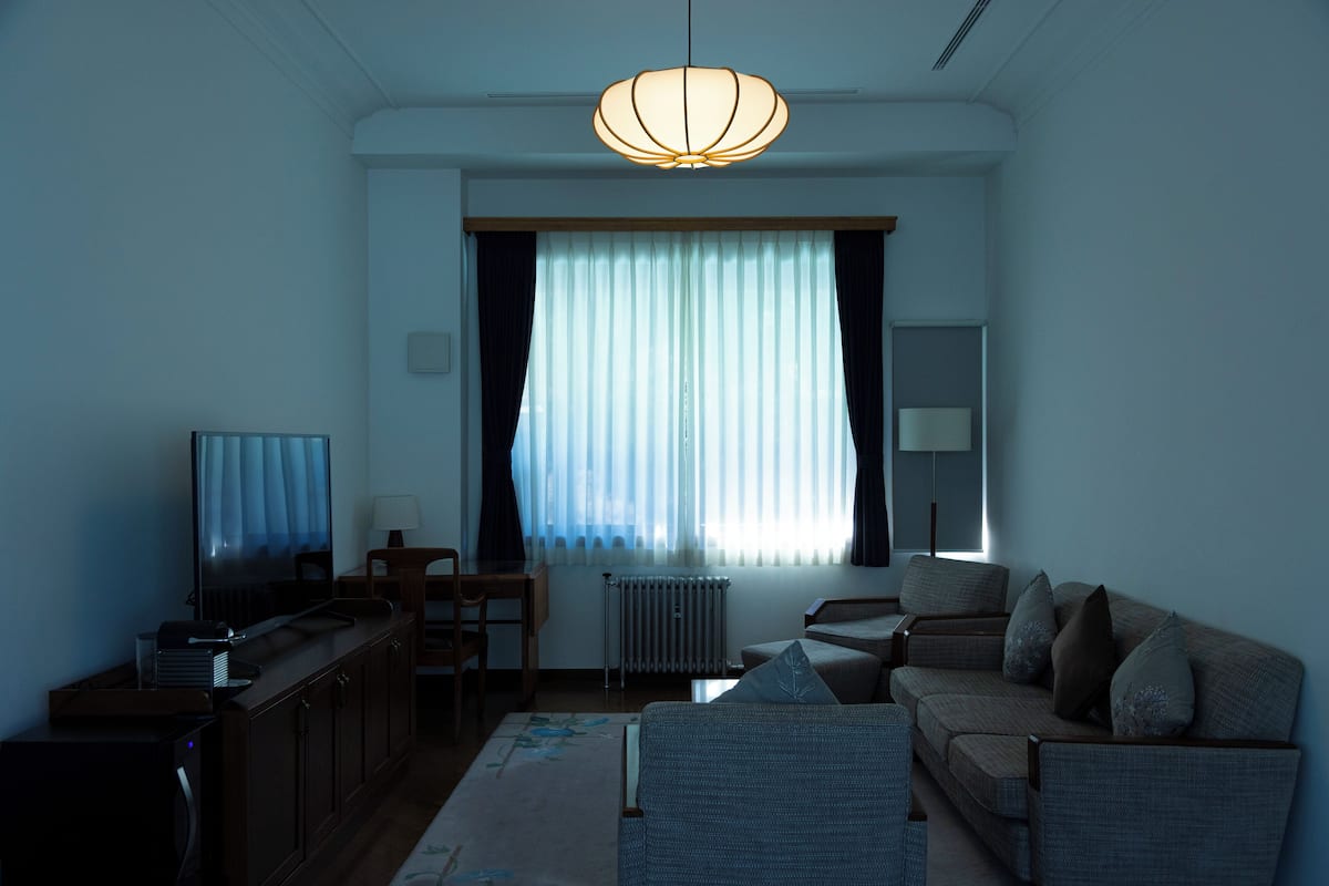 Una sala de estar con un sofá, un televisor, una mesa y una lámpara.