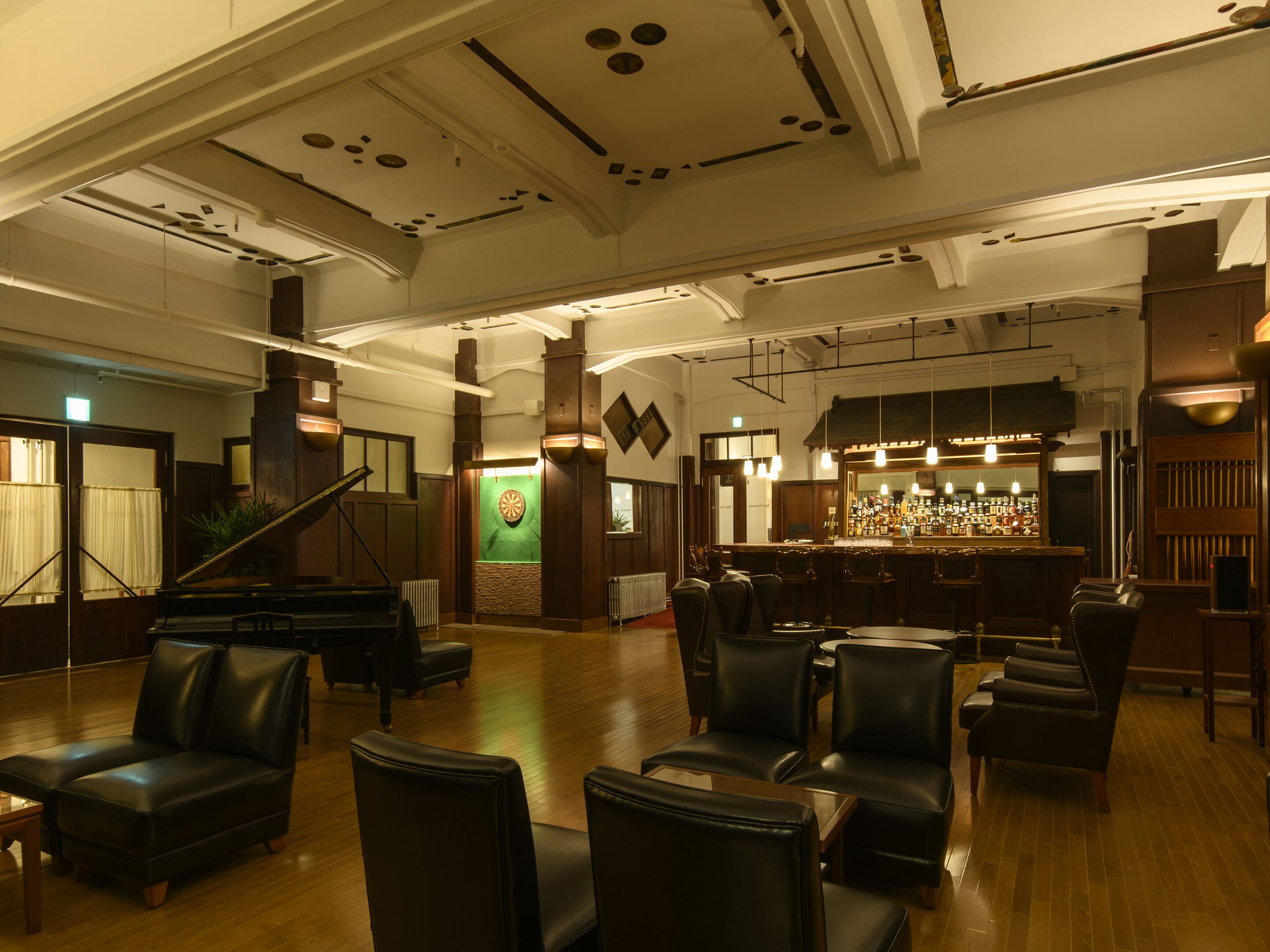 Un vestíbul ampli amb zona de bar, seients de pell i un piano.
