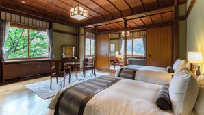 Habitación de hotel con vigas de madera, una cama grande, un escritorio y vistas a árboles desde las ventanas.
