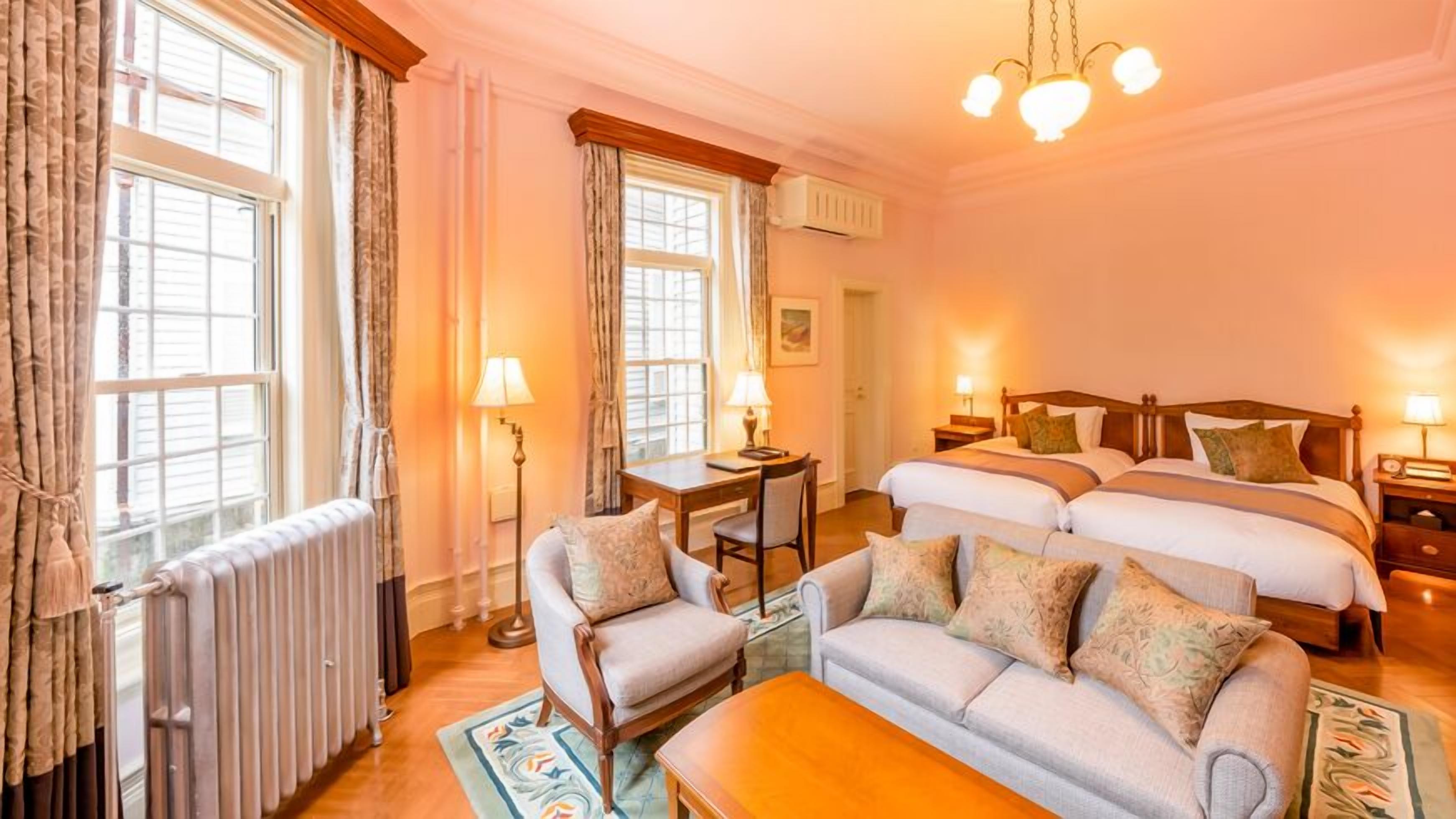 A hotel room with two beds, a sofa, a table, and a chair.