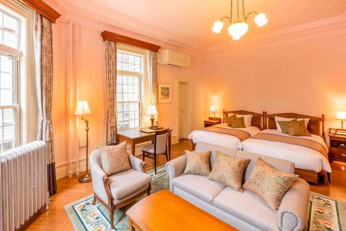 Habitación de hotel con dos camas, un sofá, una mesa y una silla.