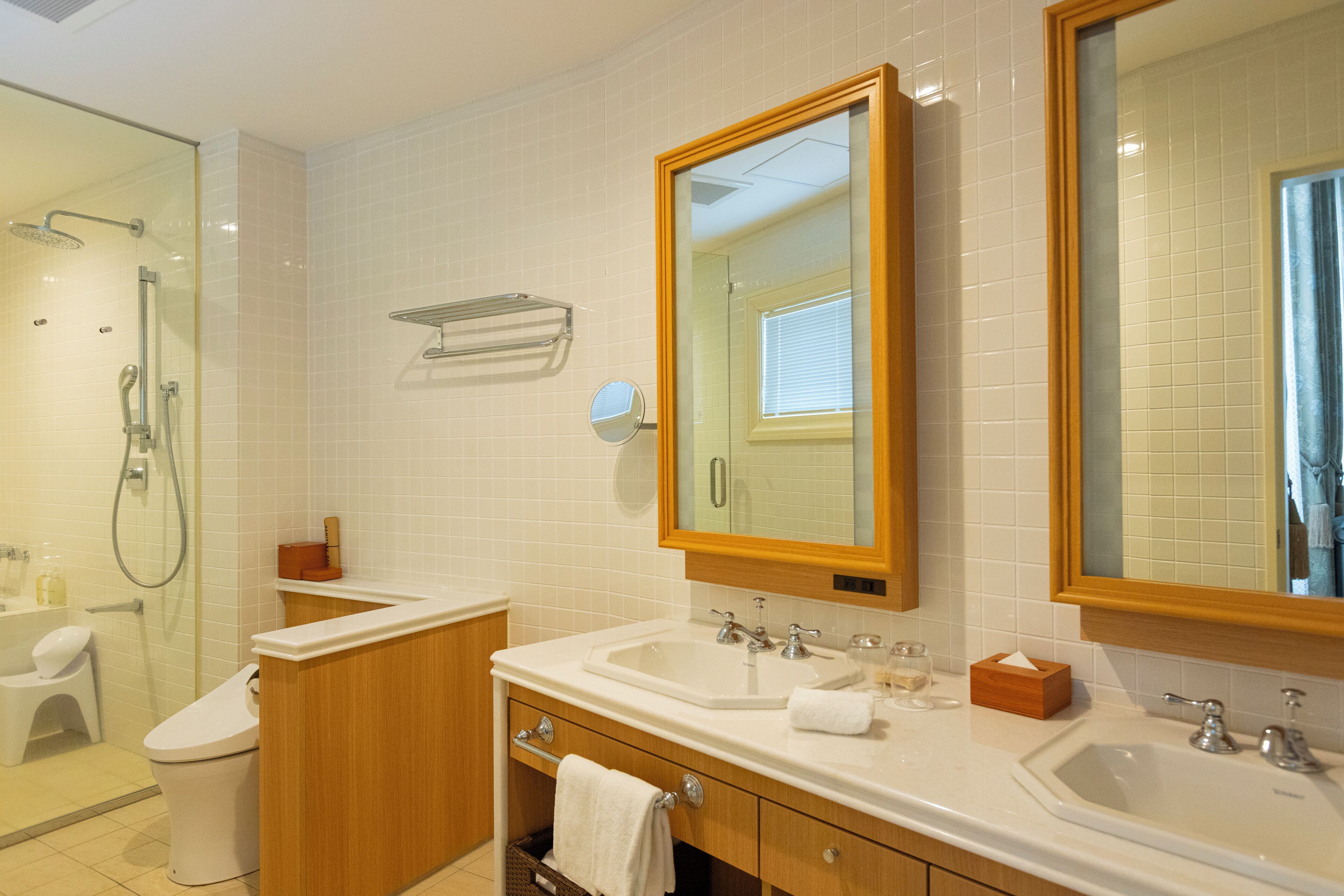 A modern bathroom with two sinks, a shower, and a toilet.