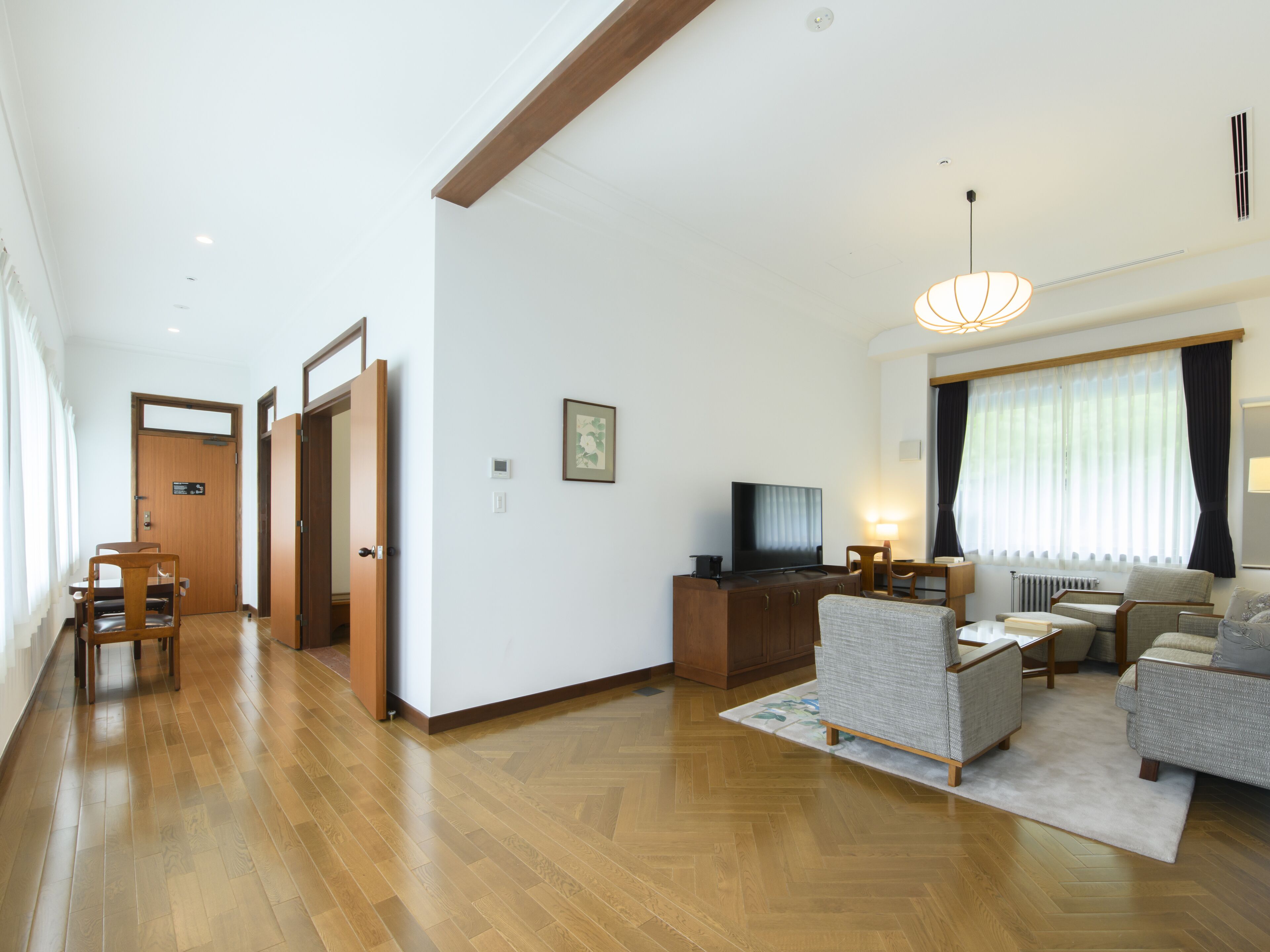 A spacious living room with a wooden floor, a television, and a sofa.
