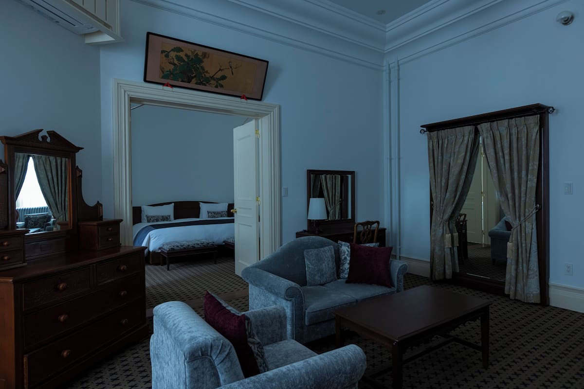Una habitación de hotel con cama, sofá, mesa, cómoda y espejo.