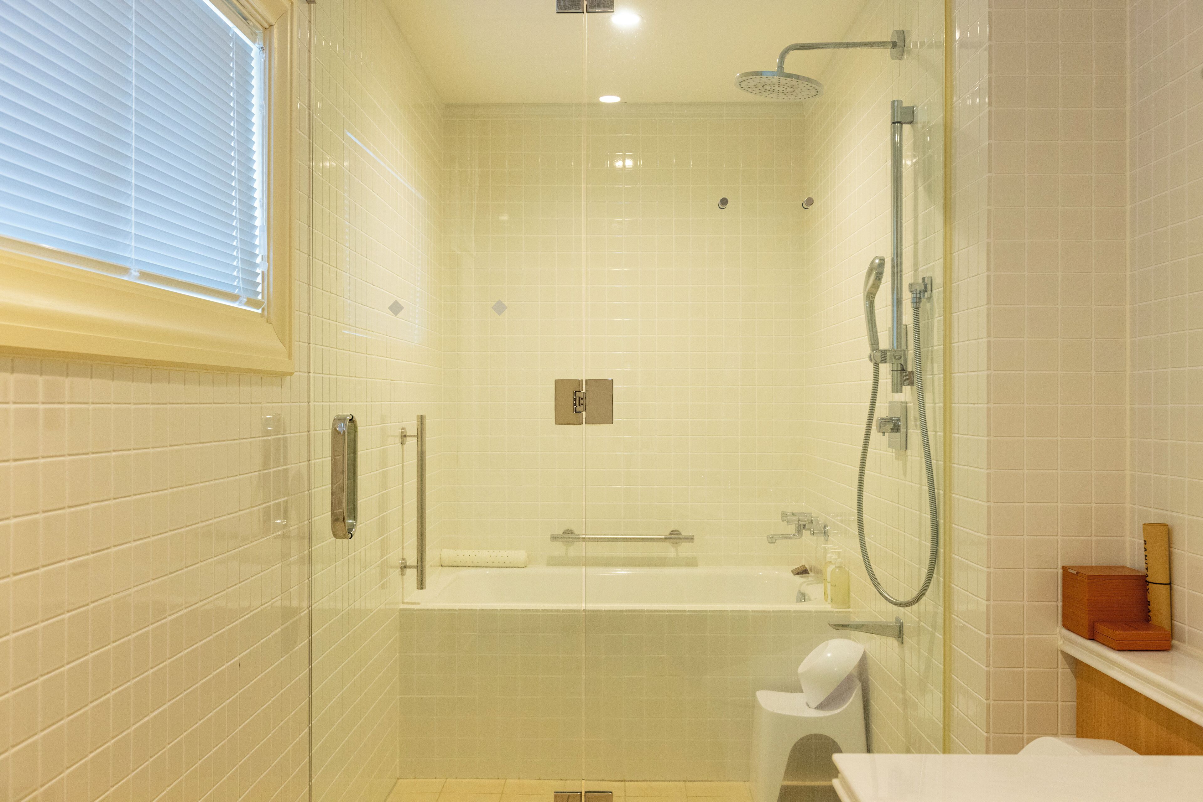 Et moderne badeværelse med brusekabine i glas, badekar og toilet.