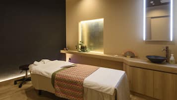 Une pièce comprenant une table de massage, un comptoir en bois avec un évier et un miroir.