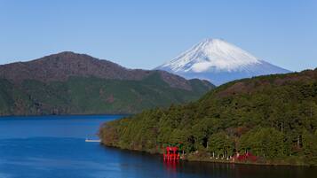 A serene lake with a red pavilion, a snow-capped mountain, and a clear sky.