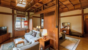 Una habitación acogedora con sofá, televisión, lámpara y espejo.