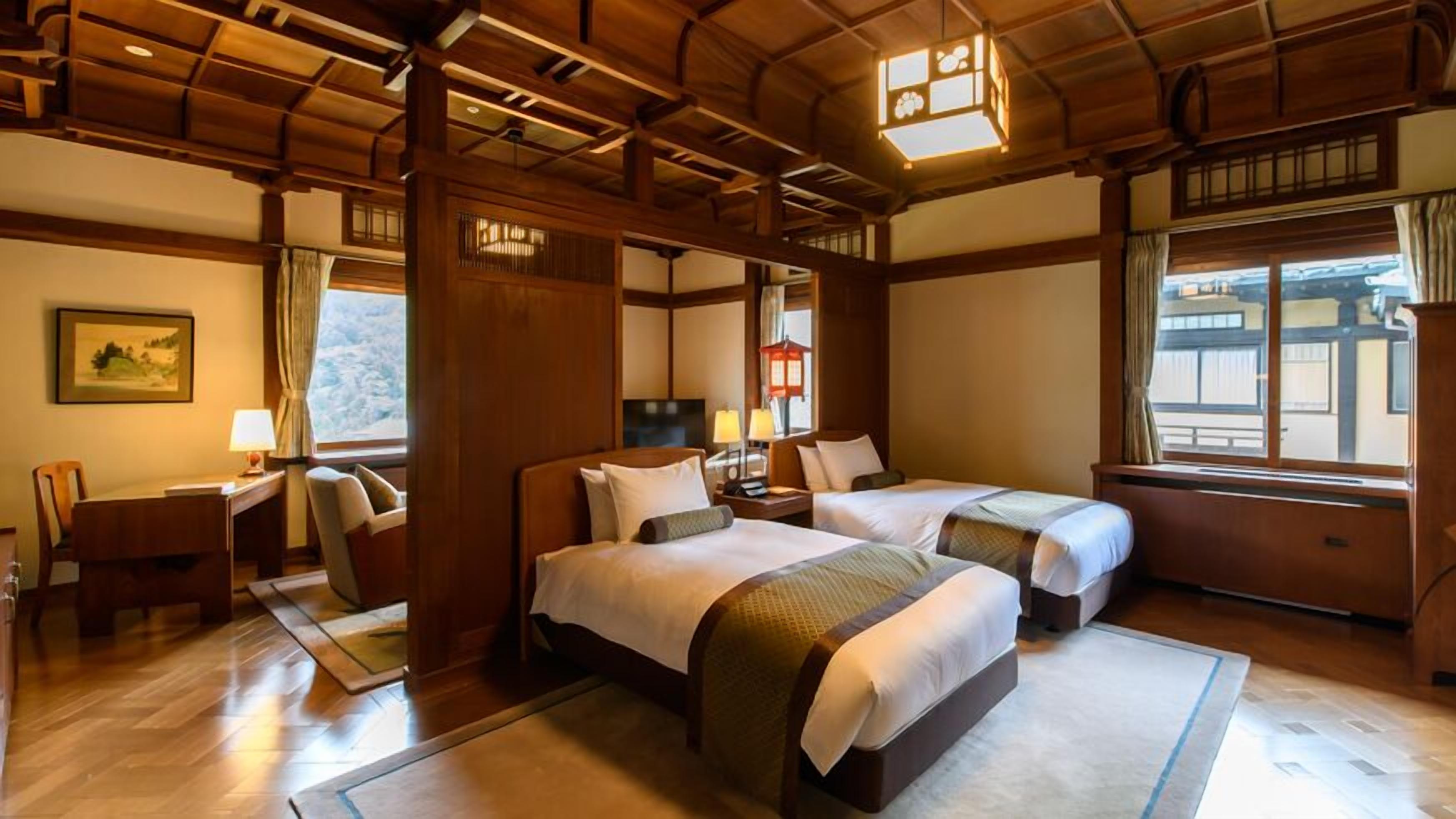 A traditional Japanese-style hotel room with wooden beams, tatami flooring, and a view of the outside.