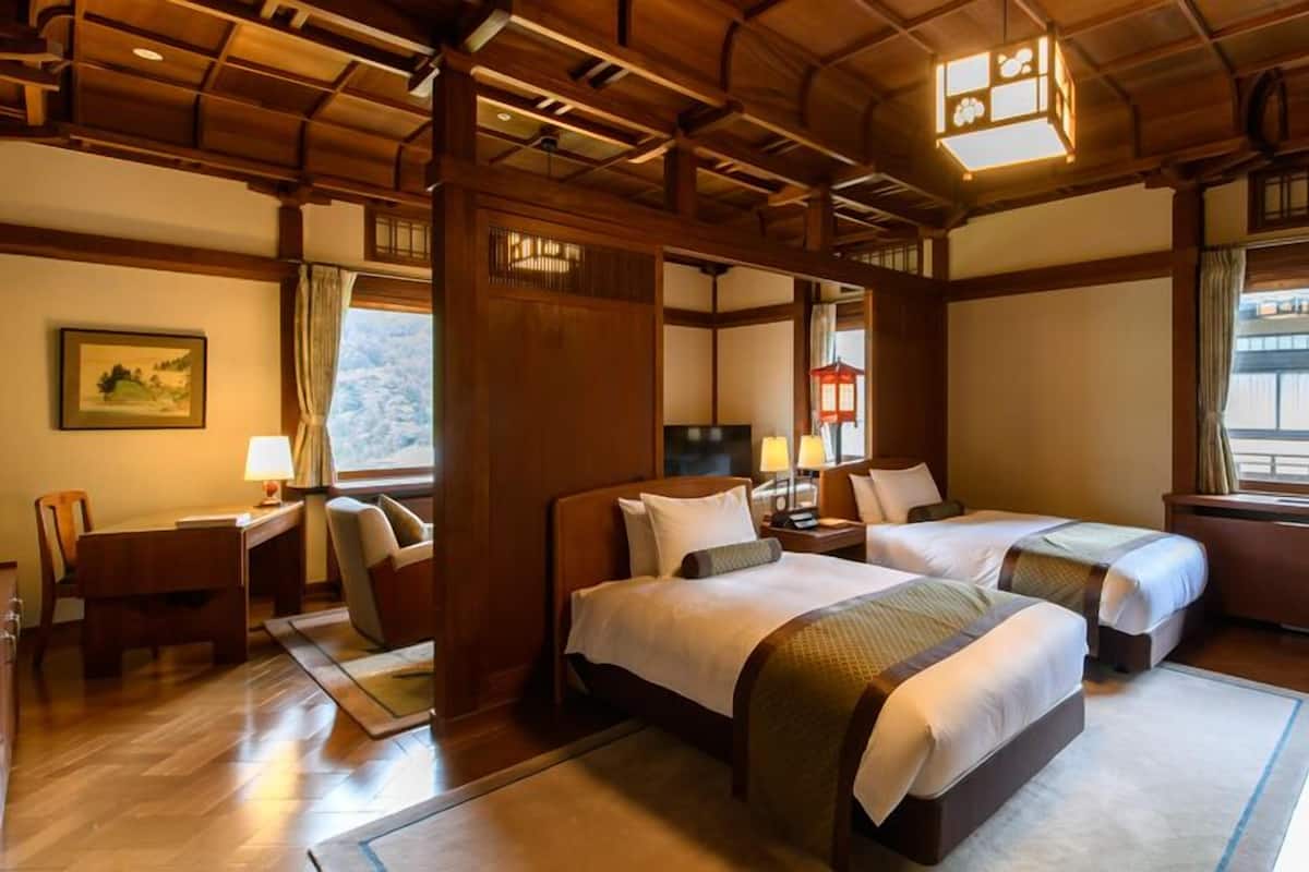 Una habitación de hotel tradicional de estilo japonés, con vigas de madera, suelo de tatami y vistas al exterior.