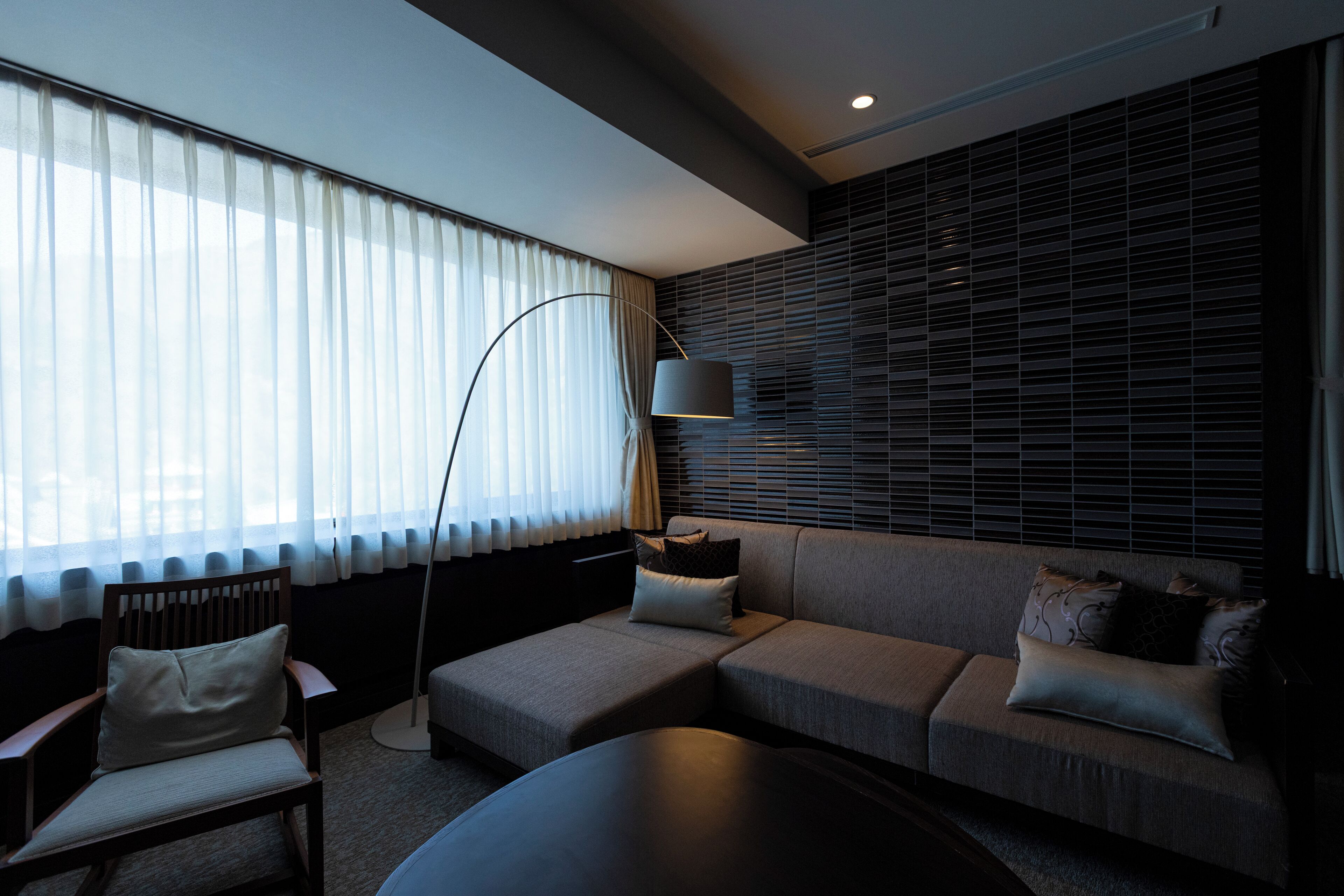 A modern living room with a sofa, armchair, and floor lamp.